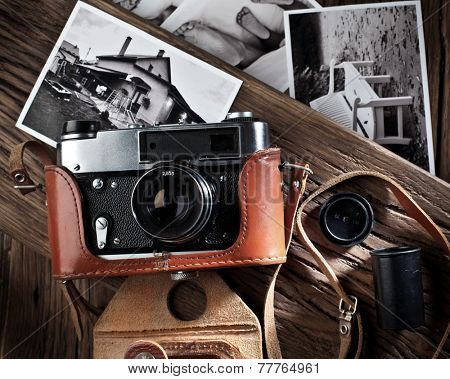 Old rangefinder camera and black-and-white photos on the old wooden table.
