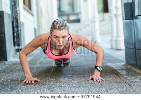 A pretty woman doing push-ups on the floor on a sunny day