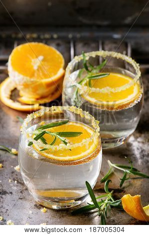Tonic water cocktail with rosemary and orange. Two glasses with zest sugar and bubbles with textile over dark texture metal background. Refreshing beverage alco non alcohol