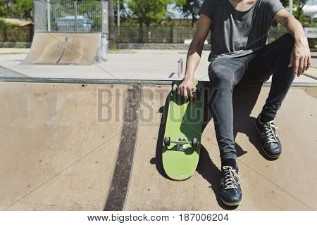 closeup of a young caucasian man with a skate board in his hand in an outdoors skate park