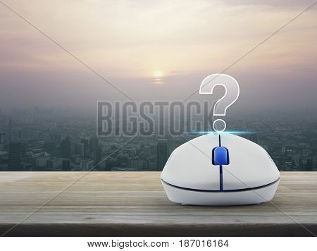 Question mark sign icon with wireless computer mouse on wooden table over modern city tower at sunset vintage style Customer support concept