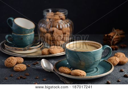 Cup of fresh coffee with Amaretti cookies on dark background, selective focus