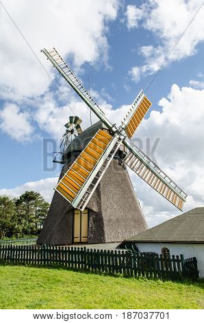 windmill with cottage and fence cloudy sky