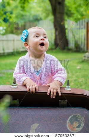 Baby sitting near suitcase in the summer garden