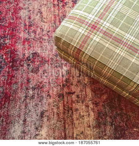 Checked textile hassock on a red vintage style carpet.