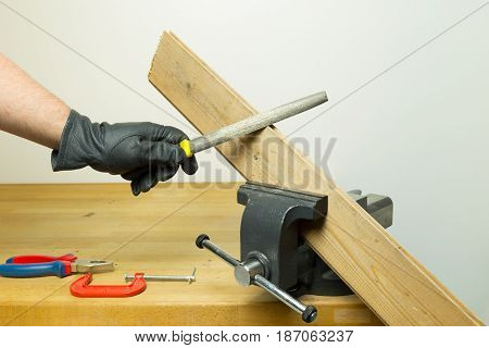 Caucasian Hands In Dark Black Leather Gloves Rasping A Piece Of Wood Board With A Rasp Chisel Hold B