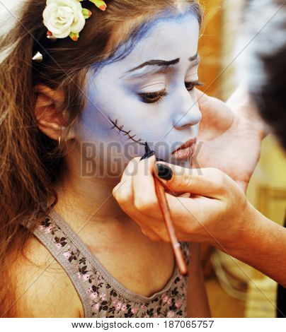 little cute child making facepaint on birthday party, zombie Apocalypse facepainting, halloween preparing concept, lifestyle people close up