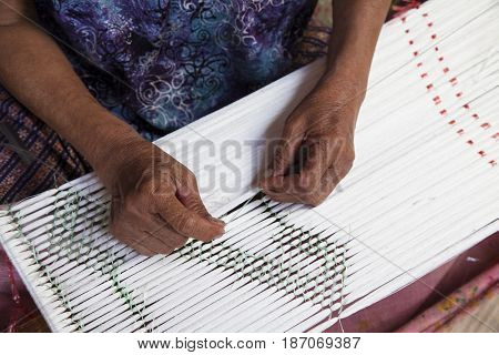 Old asia women demonstrate to procedure of making Thai Silk weaving in small weaving mill