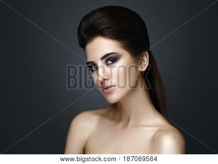 Beautiful woman with evening make-up and updo. Fashion photo. Girl ower dark background. Studio shoot.