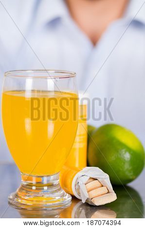 Lemon, pills of vitamin C and a glass of vitamin C dissolved over the table.