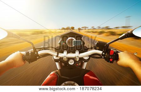Biker driving a motorcycle rides along the country road morning scene . First person angle view .