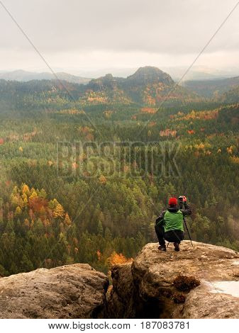 Photographer Takes Picture Of Spring Nature From Sharp Rocks. Hiker In Green Jacket Stay With Camera