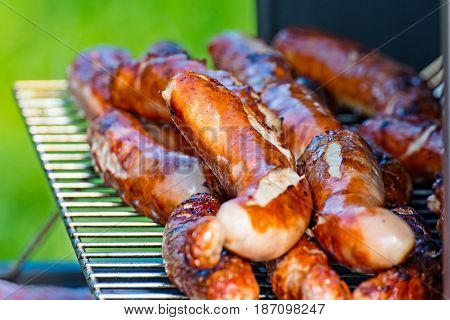 Some Brat sausages are grilled on the charcoal grill