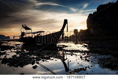 traditional long tail boat silhouette at low tide in sunset liights on Ton Sai beach, Thailand