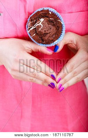 Hands making heart shape holding delicious tasty sweet chocolate muffin. Confectionery food love.