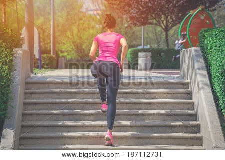 Muscular sportswoman running up on stairs. Morning workout. Urban scene. Fitness sport recreation workout healthy lifestyle concepts.