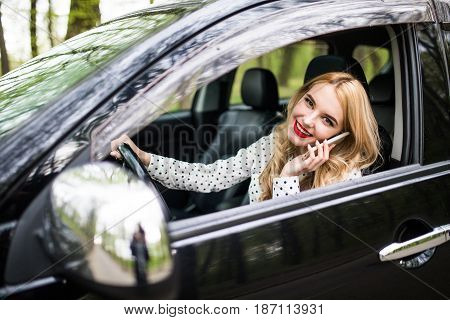 Young Woman With Telephone Having Phone Conversation While Driving Car On City Street