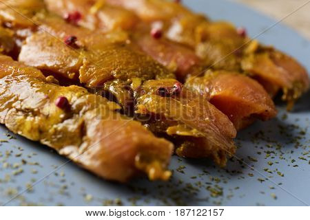 closeup of some raw spiced chicken meat skewers on a blue plate placed on a wooden table