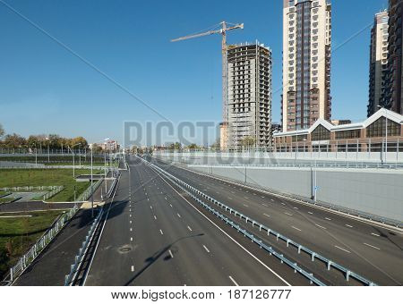 Empty highway, outgoing to the horizon. Sunny autumn day. High buildings in the background. City scape with with place for text (on the sky). Soft focus.