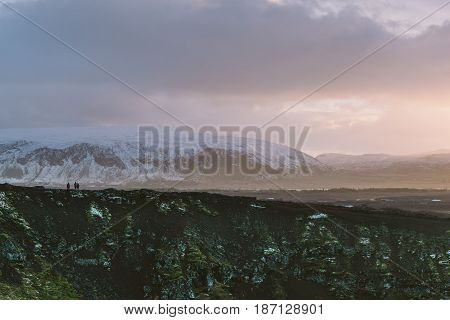 Hiking erupted volcano Kerid In South Iceland with a beautiful sunset and snowy mountains in the background