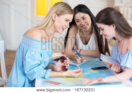 Young Beautiful Women Travelers Looking At World Map At Room, Best Friends Girls