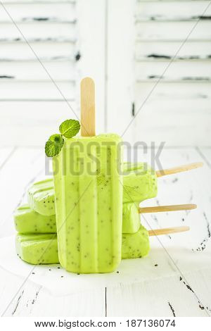 Homemade vegan green tea matcha mint coconut milk popsicles - ice pops - paletas with chia seeds on rustic white wooden background