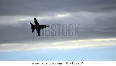 Albion Park, Australia - May 6, 2017. Silhouette of F18 Hornet fighter aircraft in flight. Clouds in the background. Wings Over Illawarra is an annual air show held at Illawarra Regional Airport.