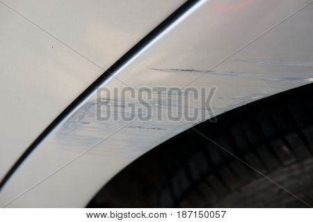 silver car wiht parking damage scratched paint on the bumber.