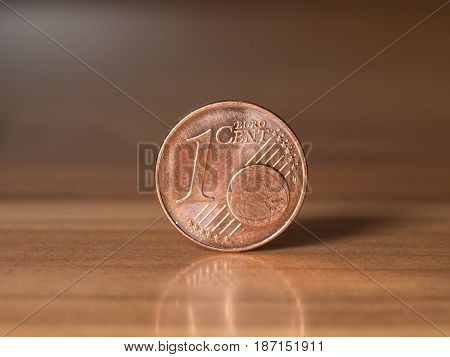 one euro cent standing on a wodden table with blurry background