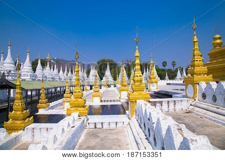 Golden Sandamuni Pagoda with row of white pagodas. Amazing architecture of Buddhist Temples at Mandalay. Myanmar (Burma) 