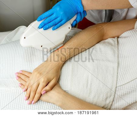 Hardware cosmetology. Depilation. Elos hair removal. Man is unrecognizable. Beautiful female hands.