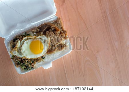Rice topped with stir-fried pork and basil on foam box