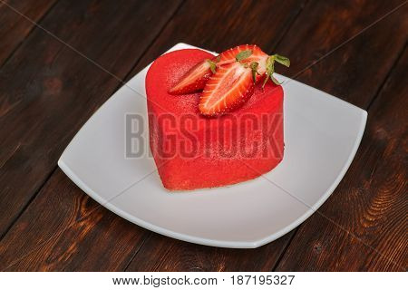 Red strawberry cake in the shape of heart on Valentine's Day on wooden background