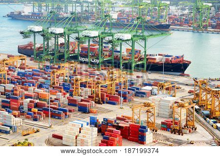 Singapore - February 17 2017: Container terminal at the Port of Singapore. Cargo ship docked in harbor. Ship-to-shore (STS) gantry cranes loading and unloading vessels at shipping yard.