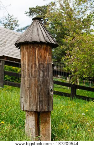 Old traditional ukrainian wooden beehive, green grass, trees and wooden fence background