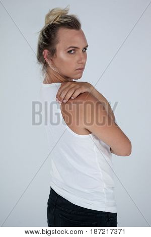 Portrait of beautiful transgender woman looking over shoulder against gray background