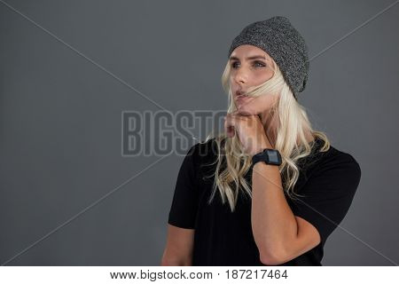 Thoughtful transgender woman wearing knit hat gray background