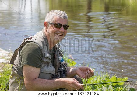 A fisherman with a pole hunts trout. A handsome man flying on the river Otava South Bohemia Czech republic.
