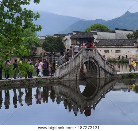 HONGCUN CHINA - APRIL 20 2014: Tourist walking around Moon Lake in Hongcun Village China. Hongcun is ancient village in Anhui Province near the southwest of Mount Huangshan.