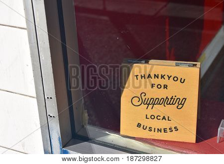 shop front window with thank you for shopping local sign