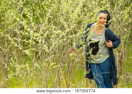 Posing beauty woman in sunny day with little young trees