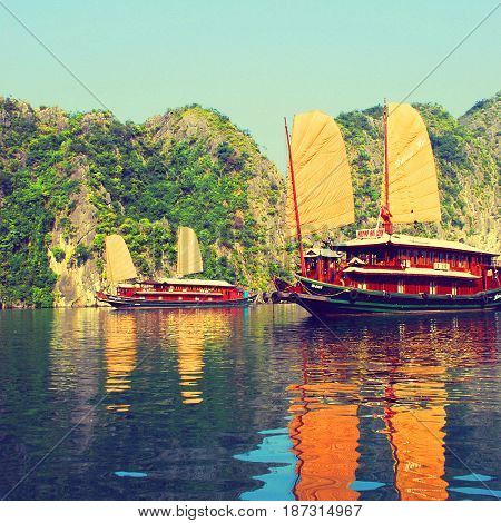 Traditional sailing junks reflecting on the calm waters of Halong Bay Vietnam