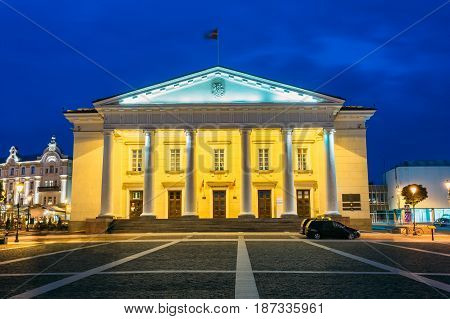 Vilnius, Lithuania. Main Facade Of Town Council In Evening Illumination, Administrative Building With Columns On Didzioji Street In Old Town Under Summer Blue Sky.