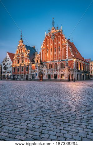 Riga, Latvia. Schwabe House And House Of The Blackheads At Town Hall Square, Ancient Historical Landmark And Popular Touristic Showplace In Summer Evening. Night Illuminations