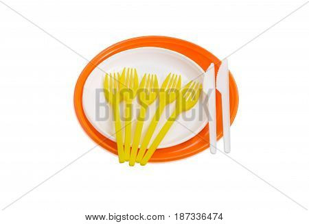 Orange and white disposable plastic plates different sizes plastic disposable yellow forks and white knives on a light background
