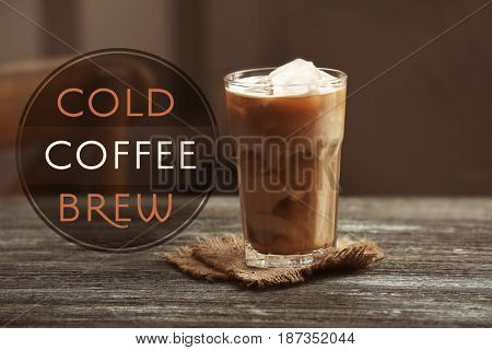 Glass of cold brewed coffee with milk on wooden table