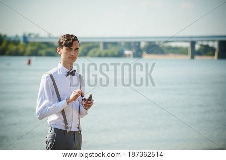 Young Skinny Man, Elegantly Stylishly Dressed In White Shirt, Trousers With Suspenders And Bow Tie.