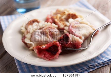 Traditional Polish dumplings Pierogi ruskie with sour cherry on a rustic table