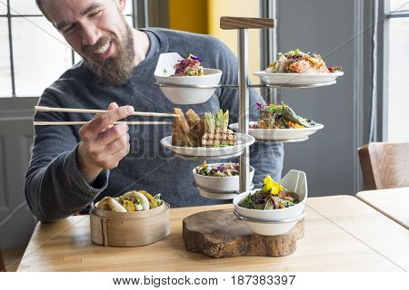 Man Picks Fried Tofu Using Chopsticks From Plate In Restaurant