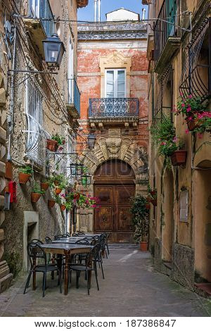 Cafe tables and chairs outside in old cozy street in the Positano town Italy